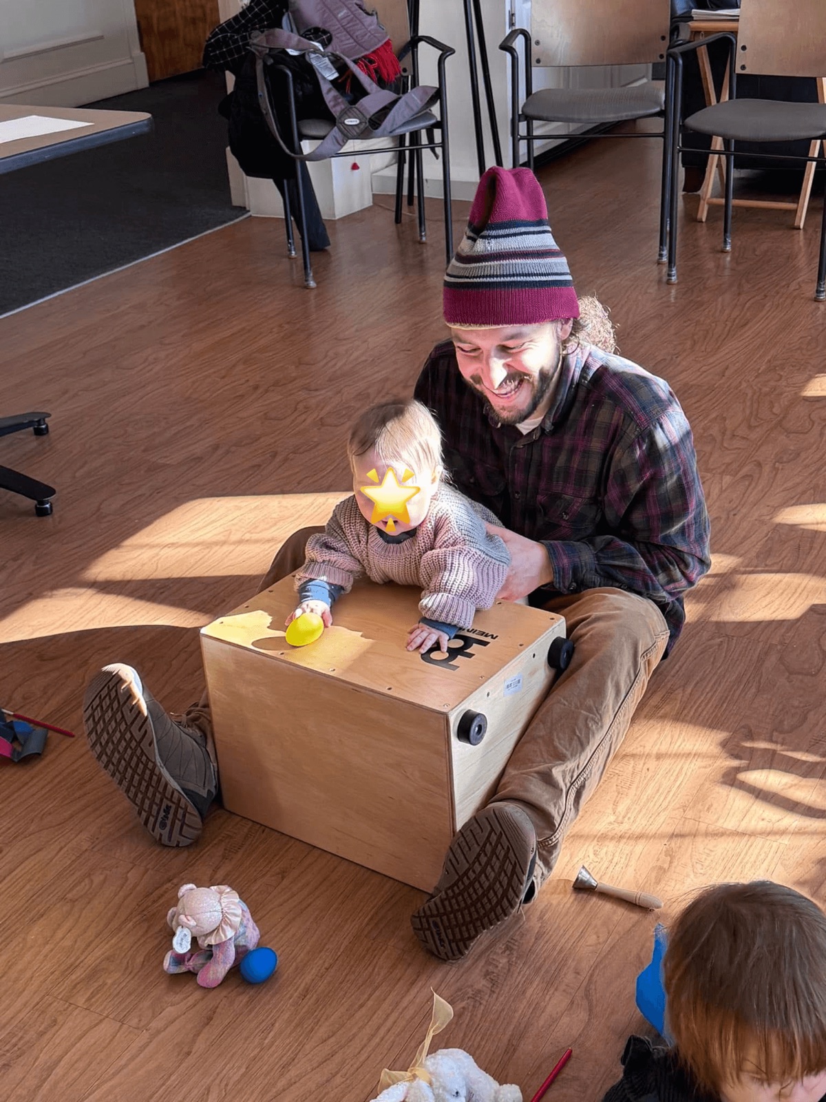 A dad and his baby playing a cajon drum together during class